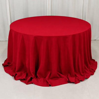 Round table with red tablecloth draped to the floor in a white room
