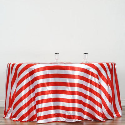 Red and white striped tablecloth draped over a round table with glassware.