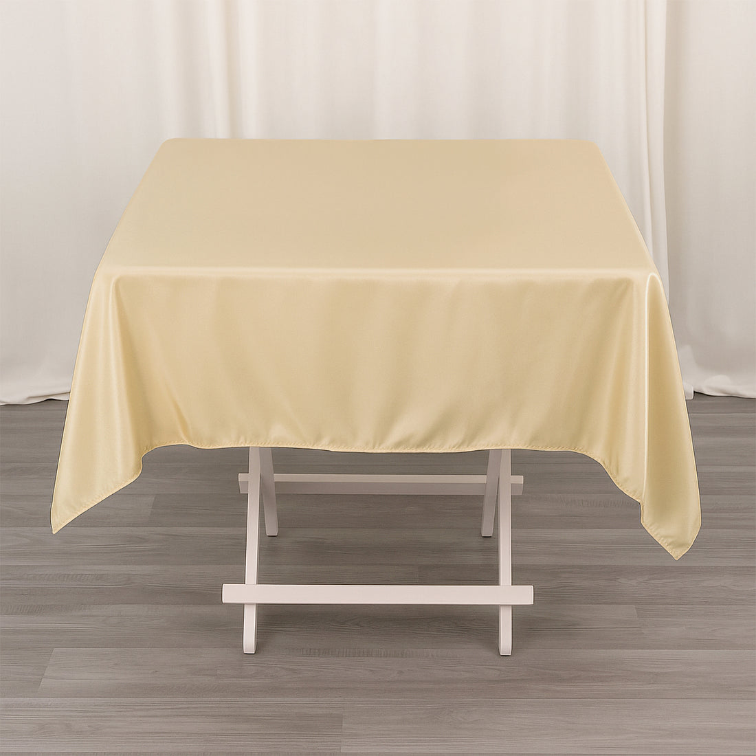 Beige tablecloth draped over a white table in a studio setting.