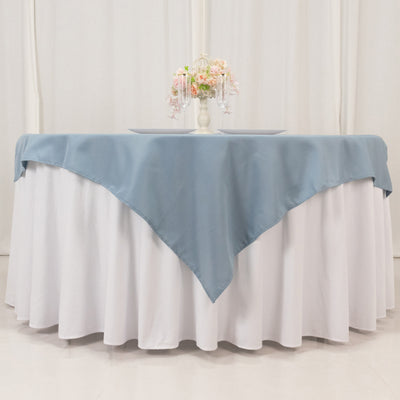 Elegant blue tablecloth draped over a white table with floral centerpiece.
