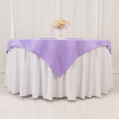 Lavender tablecloth draped over a round table with floral centerpiece.
