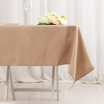 Beige tablecloth draped over a table with a floral centerpiece.
