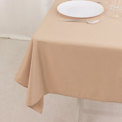 Beige tablecloth draped over a table set with a plate and cutlery.
