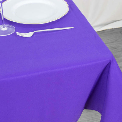 Purple tablecloth draped over a table with a plate and fork.