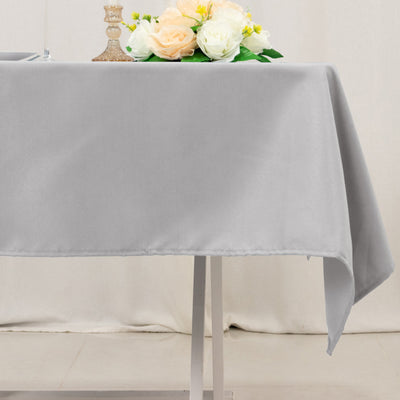 Grey tablecloth draped on a table with decorative flowers on top.