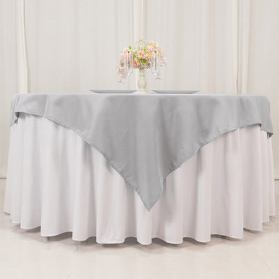 Gray tablecloth draped over a round white table with floral centerpiece.