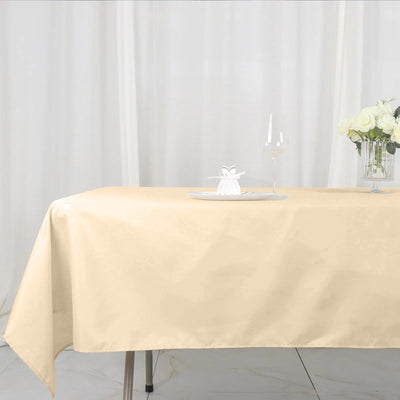 Beige tablecloth draped elegantly over a table with a glass and flowers.