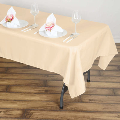 Beige tablecloth on a dining table set with plates and glasses.