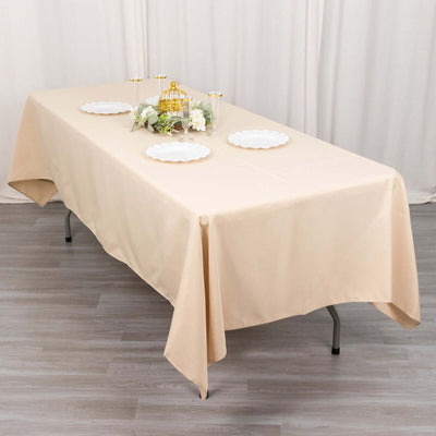 Beige tablecloth draped over a table set with plates and floral decor.