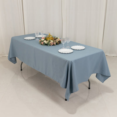 Blue tablecloth draped over a folding table set with plates and floral centerpiece.
