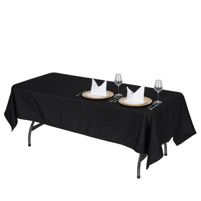 Black tablecloth on a dining table set with plates and glassware.