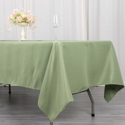 Green tablecloth draped over a table with a glass and floral centerpiece.