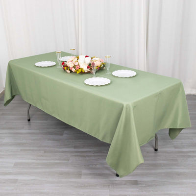 Green tablecloth draped over a table with floral centerpiece and plates.