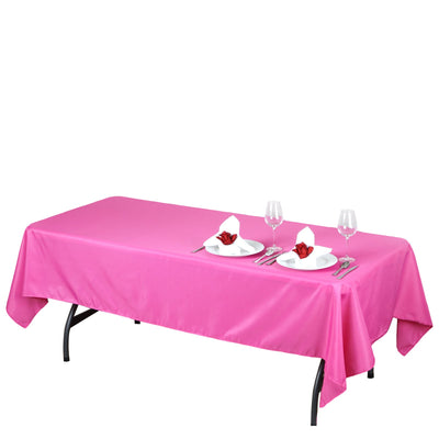 Pink tablecloth draped over a table set with plates and glasses.