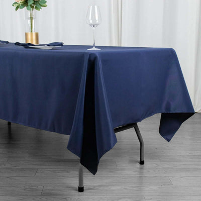 Navy blue tablecloth draping a table with a glass and plant centerpiece.