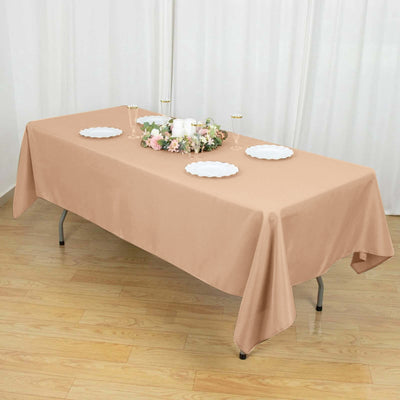 Beige tablecloth draped over a table set for a gathering with decorative centerpiece.