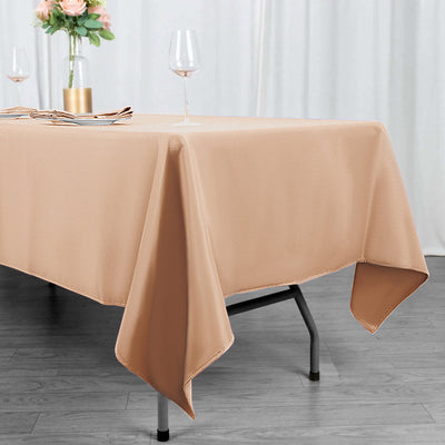 Beige tablecloth draped on a table with wine glasses and floral centerpiece.