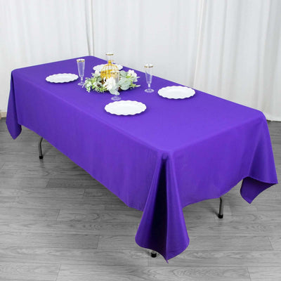 Purple tablecloth draped over a table with decorative plates and floral centerpiece.
