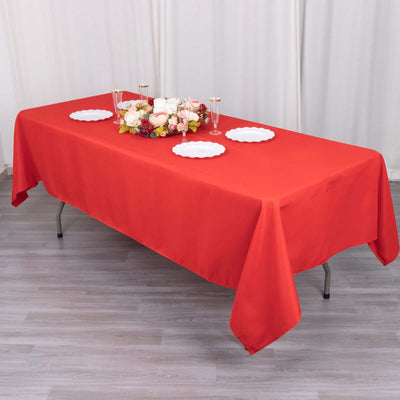 Red tablecloth draped over a table with white plates and floral centerpiece.