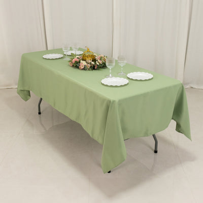 Green tablecloth draped over a folding table with dinnerware and floral centerpiece.