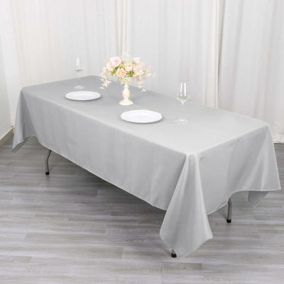 Gray tablecloth draped over a table set for dining with plates and a floral centerpiece.
