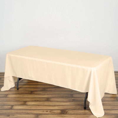 Beige tablecloth draped over a rectangular table on a wooden floor.