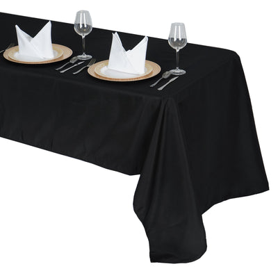 Black tablecloth draped over a table set for dining with plates and glasses.