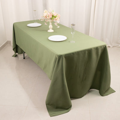 Olive green tablecloth draped elegantly over a table with plates and glasses.
