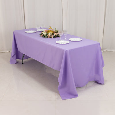 Purple tablecloth draped over a table set with plates and floral centerpiece.