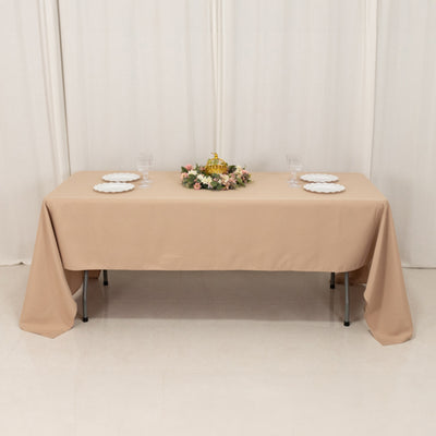 Beige tablecloth draped over a table with plates and floral centerpiece.