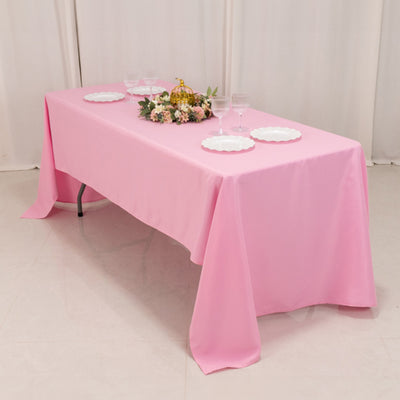 Pink tablecloth draped over a table set with floral centerpiece and dishes.