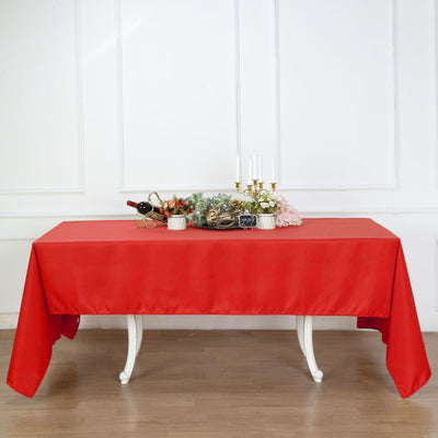 Red tablecloth draped over a white table with decorative items on top.