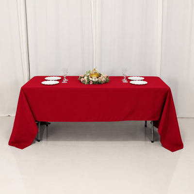 Elegant red tablecloth dining table with floral centerpiece and glassware