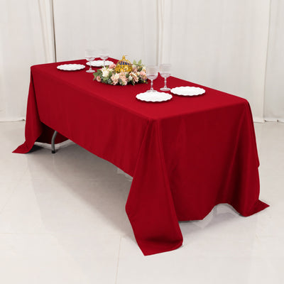 Red tablecloth dining table with plates, wine glasses, and floral centerpiece