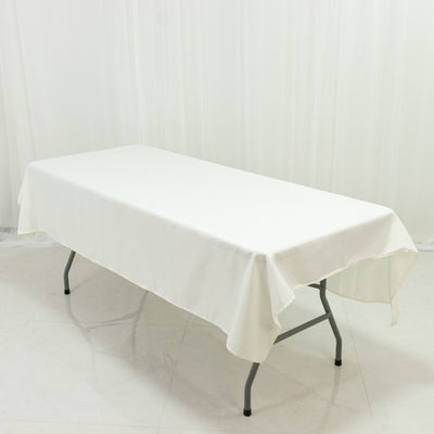 White table with a fitted tablecloth on a plain backdrop