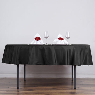 Elegant black tablecloth with white napkins and red roses for dining setup.