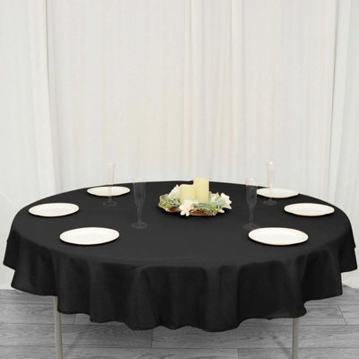 Round black tablecloth with decorative centerpiece and dinnerware set.