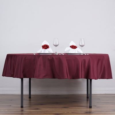 Elegant dining table setup with burgundy tablecloth and rose-adorned napkins.