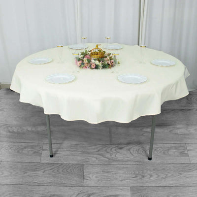Round table set with a cream tablecloth and decorative centerpiece.