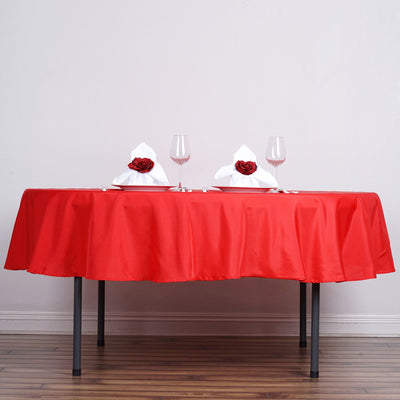 Elegant red table setting with white napkins and roses.