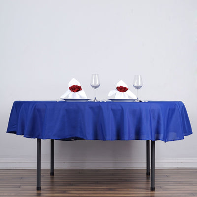 Elegant blue tablecloth with white napkins and red roses on a dining table.