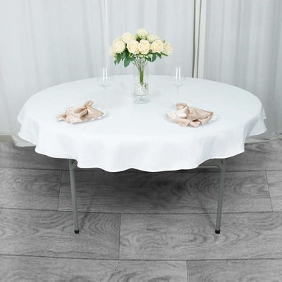 Round white table with an elegant table setting and floral centerpiece.