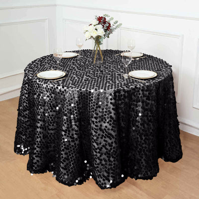 Black sequin tablecloth on a round table with plates and floral centerpiece