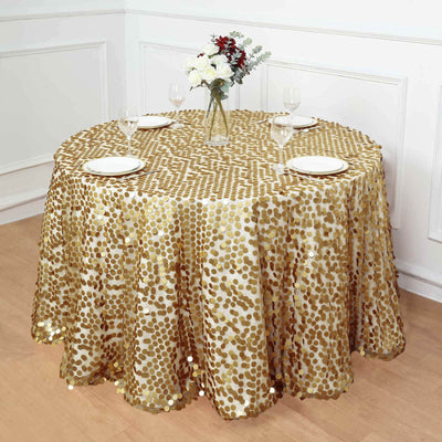 Gold sequin tablecloth on a round table with plates and vase of flowers.