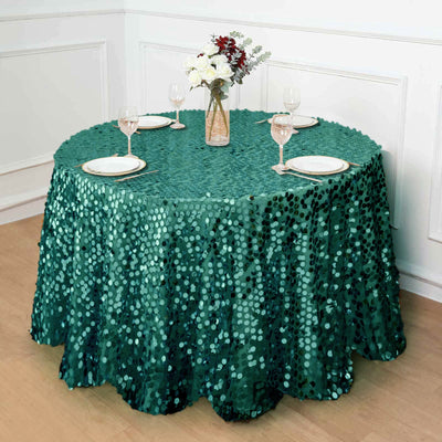 Green sequin tablecloth draping a round dining table set with plates and glasses.