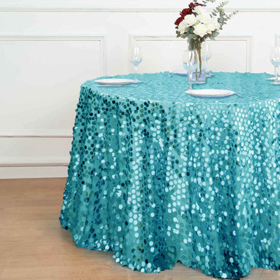 Teal sequin tablecloth draped on a round table with floral centerpiece.