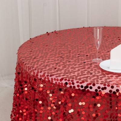 Red sequin tablecloth on round table with glass and plate