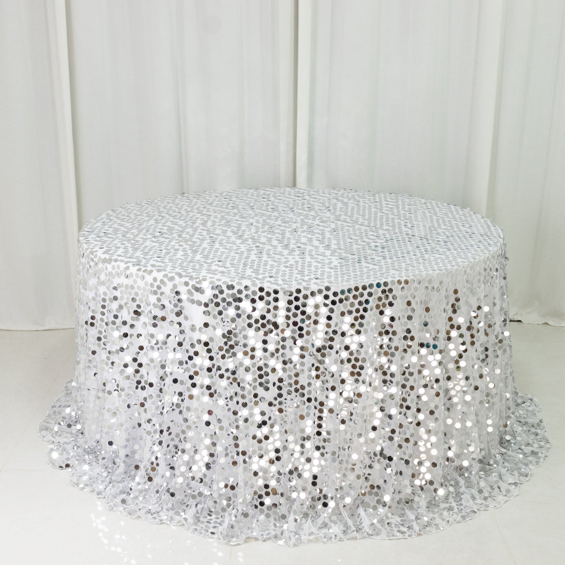 Round silver sequin table cover on a white backdrop.