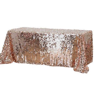 Rose gold sequin tablecloth with shimmering texture and draped edges.