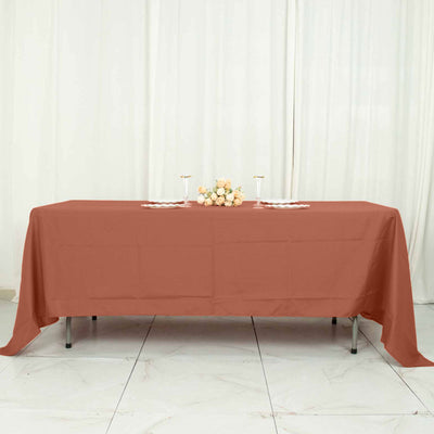 Rust-colored tablecloth on a table with flowers and glasses in a staged setting.